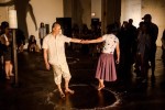 Barefoot dancers hold hands and lean away from each other
