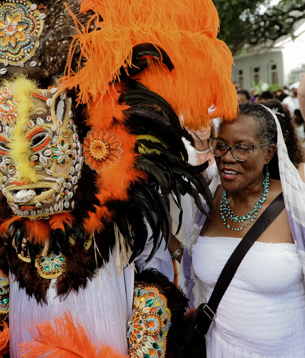 Participants in the MAAFA commemoration festival, featuring a large feathered mask decorated with seashells and beads