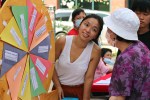 A woman smiles as she runs a homemade spinning prize wheel at an outdoor block party